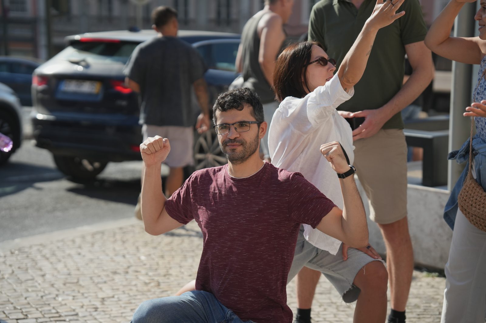 A player celebrates with arms raised while teammates cheer on a Lisbon street